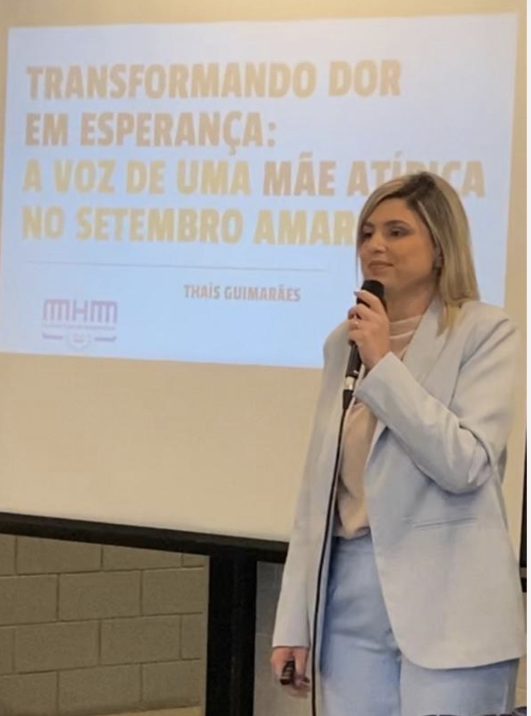 Thaís Guimarães ao microfone em palestra de Setembro Amarelo para empresas